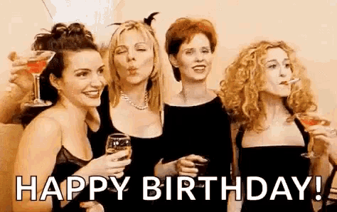 a group of women are standing next to each other holding glasses of wine and blowing a kiss .