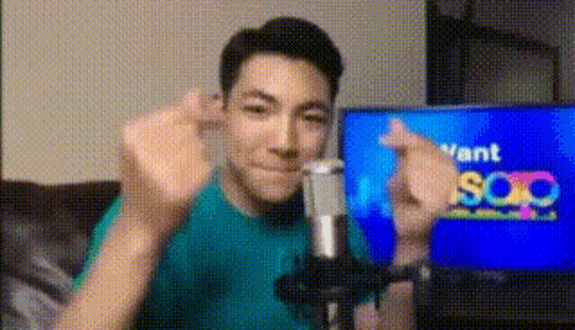 a young man is giving the middle finger in front of a microphone while sitting on a couch .