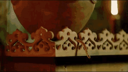 a snake is crawling on a wooden shelf next to a bowl