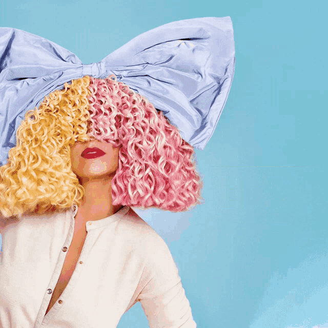 a woman with curly hair and a blue bow on her head stands in front of a sign that says #spa