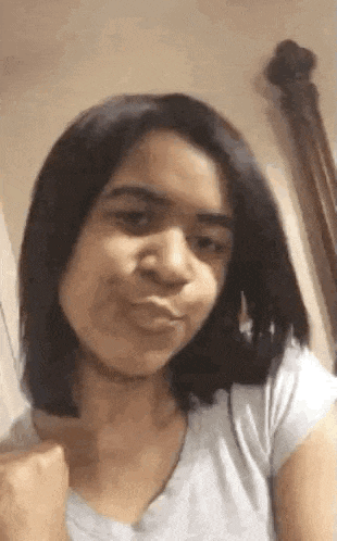 a young girl is making a funny face while taking a selfie in a bathroom .