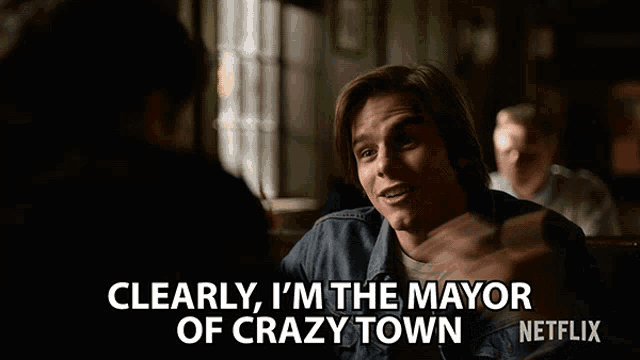 a man sitting at a table with the words clearly i 'm the mayor of crazy town on the bottom