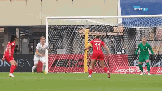 a female soccer player wearing the number 11 jersey kicks the ball into the goal