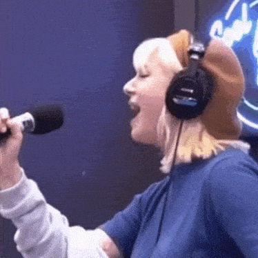 a woman wearing headphones is singing into a microphone ..