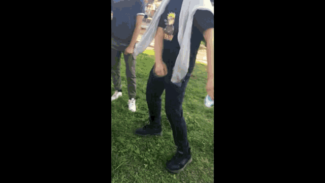 a man in a black shirt is dancing in the grass
