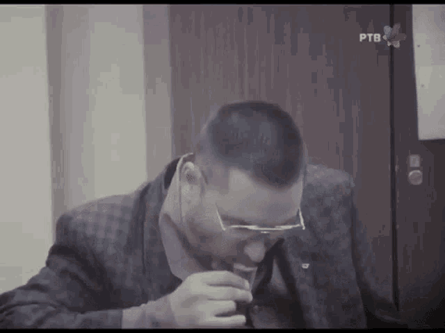 a man in a suit and tie is smoking a cigarette in front of a ptb sign