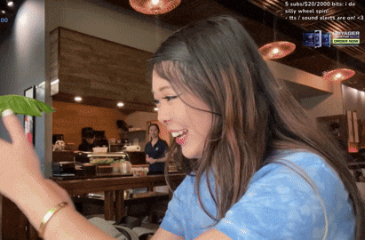 a woman in a blue shirt is smiling in front of a screen that says 00