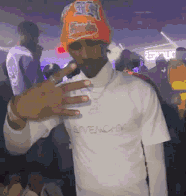 a man wearing a beanie and a white shirt is standing in a crowd .
