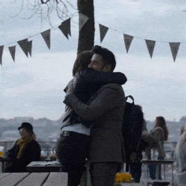 a man in a suit and a woman in a leather jacket are hugging each other
