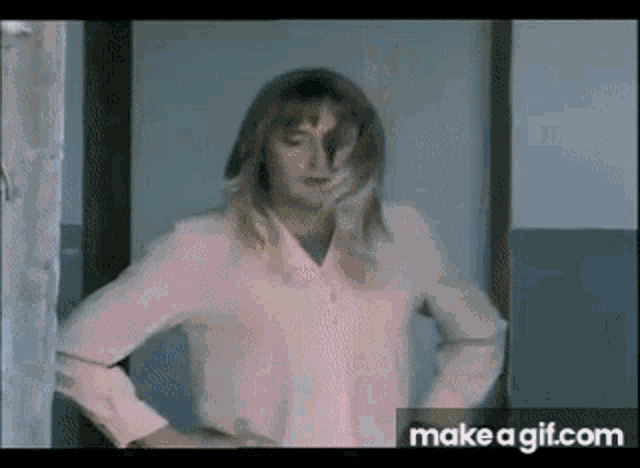 a woman in a pink shirt is standing in a hallway .