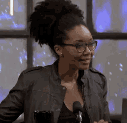 a woman wearing glasses and a leather jacket is smiling