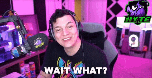 a man wearing headphones is sitting in front of a microphone and saying wait what