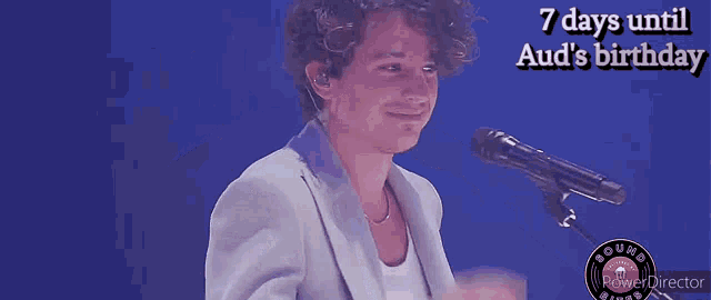 a man singing into a microphone with the words 7 days until aud 's birthday on the bottom