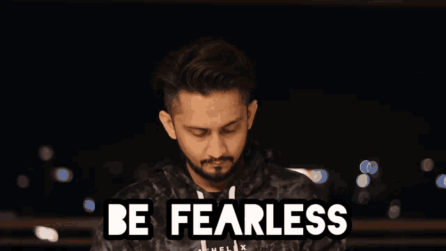 a man with a beard stands in front of a sign that says " be fearless "