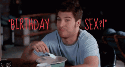 a man is sitting at a table with a spoon in his mouth and the words " birthday sex ? " behind him