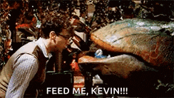 a man is standing next to a monster that says feed me kevin