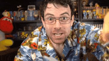 a man wearing glasses and a hawaiian shirt looks at the camera