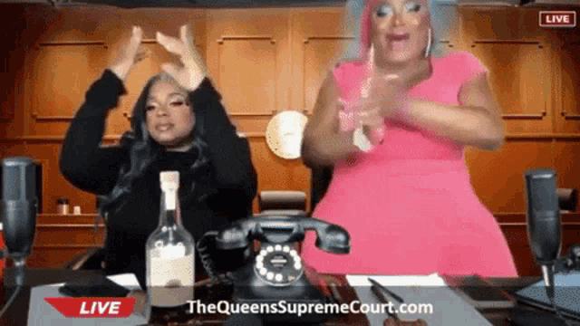two women are dancing in front of a live advertisement for the queens supreme court