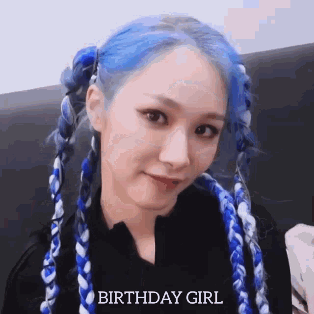 a woman with blue hair and braids is sitting on a couch .