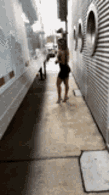 a woman in a black dress is walking down a sidewalk .