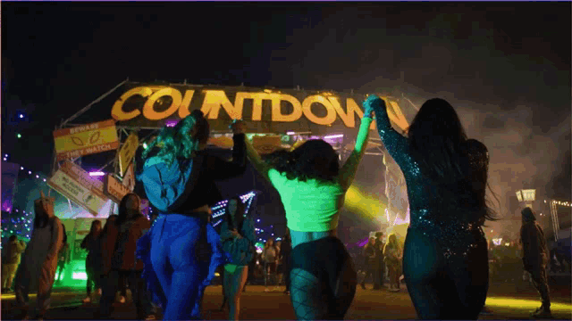 a group of women are dancing in front of a countdown sign