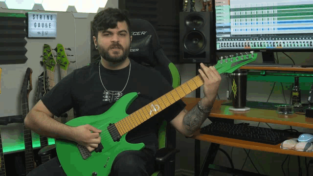 a man is playing a green guitar in front of a string gauge sign