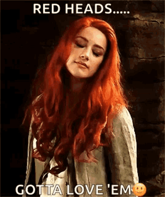 a woman with red hair is standing in front of a brick wall with her eyes closed .