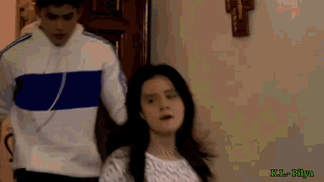 a man in a blue and white adidas shirt stands next to a woman in a room
