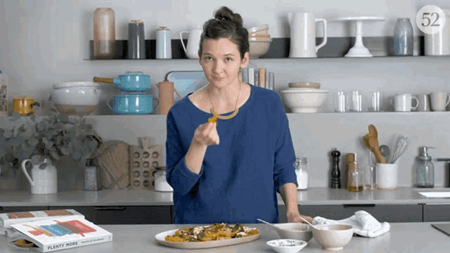 a woman in a kitchen with a book titled plenty more on the counter
