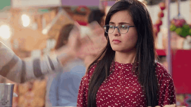 a woman wearing glasses and a red top is looking at something