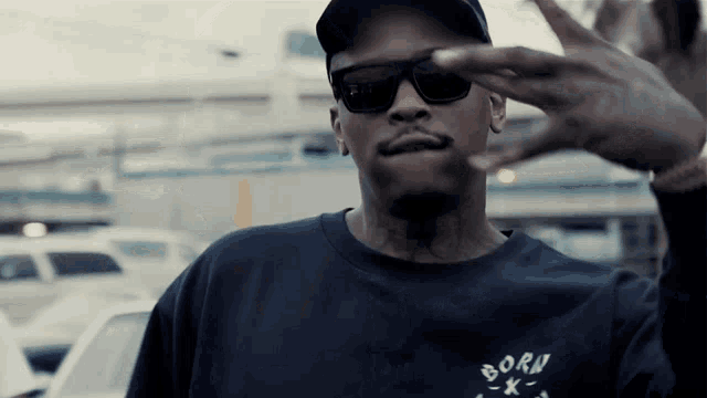 a man wearing sunglasses and a black shirt that says born