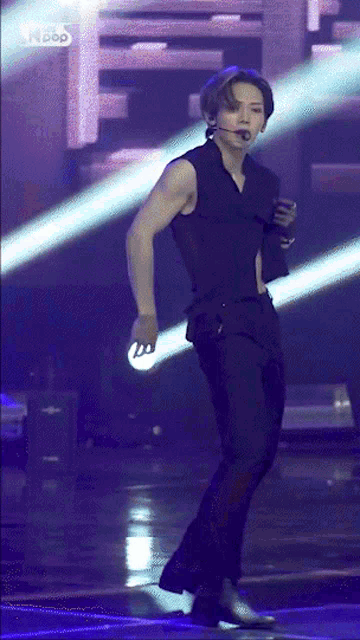 a man in a black vest is standing on a stage in front of a sign that says ' i-pop ' on it