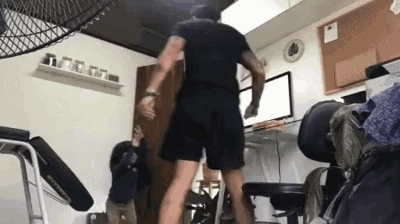 a man in a black shirt and shorts is dancing in a room .