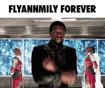 a man in a black jacket is standing in front of a screen that says flyannmily forever