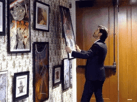 a man is hanging a picture on a wall