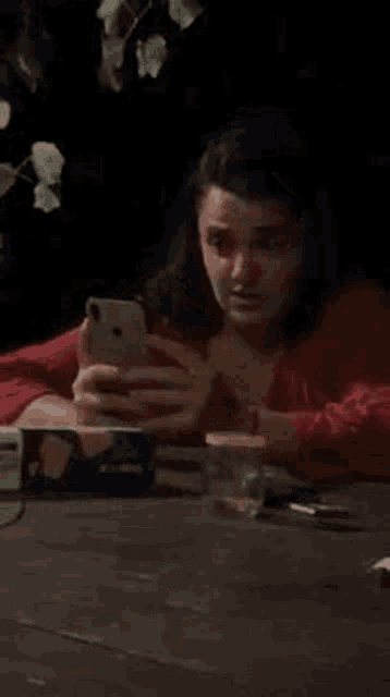 a woman is sitting at a table with a cell phone in her hand .