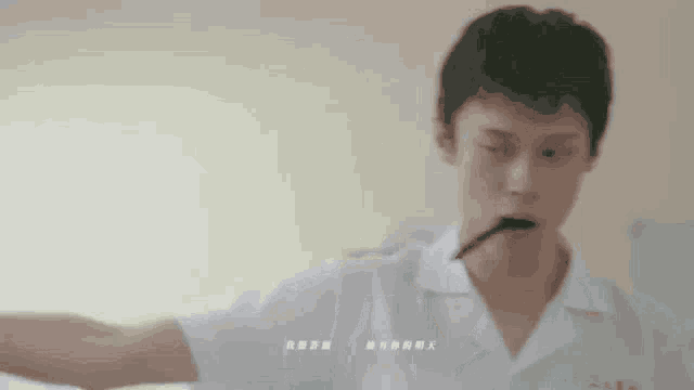 a man in a white shirt is holding a stick in his mouth with chinese writing below him