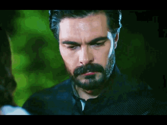 a man with a beard and mustache is looking down at something