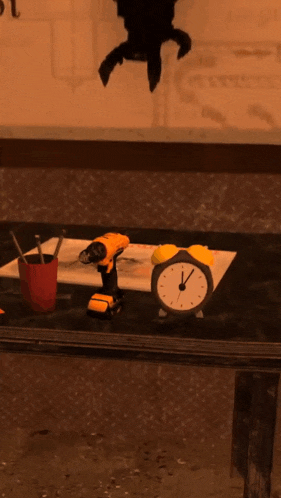 a drill sits on a table next to an alarm clock and a piece of paper that says " acht tempel "