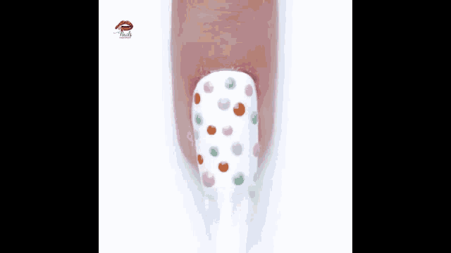 a woman 's nails are painted white and decorated with polka dots .