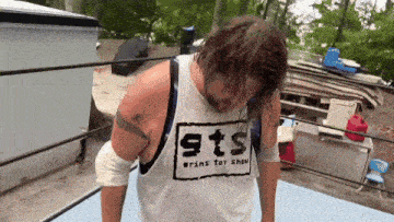 a man wearing a white tank top that says sts