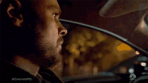 a man with a beard is sitting in a car at night .