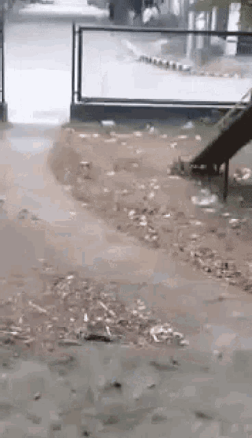 a person is walking down a sidewalk next to a slide .