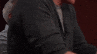 two men are laughing and one of them has a microphone on his neck