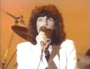 a man singing into a microphone in front of a drum set