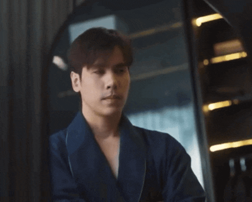 a young man in a blue robe is standing in front of a mirror
