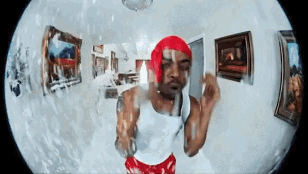 a man in a red headband is dancing in a room with paintings on the walls