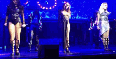 a group of women are dancing on a stage in front of a crowd .