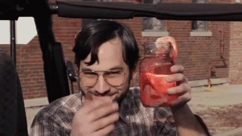 a man in a plaid shirt is holding a mason jar with a drink in it