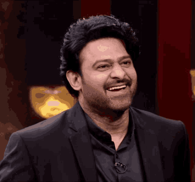 a man wearing a black suit and black shirt smiles